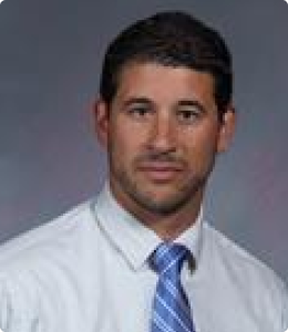 man with dark hair with white collar shirt and blue tie